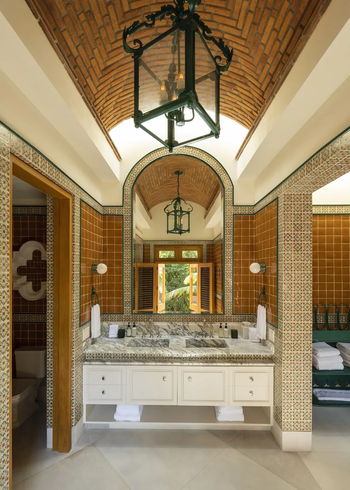 A brick-vaulted ensuite bathroom with a double vanity and folded towels