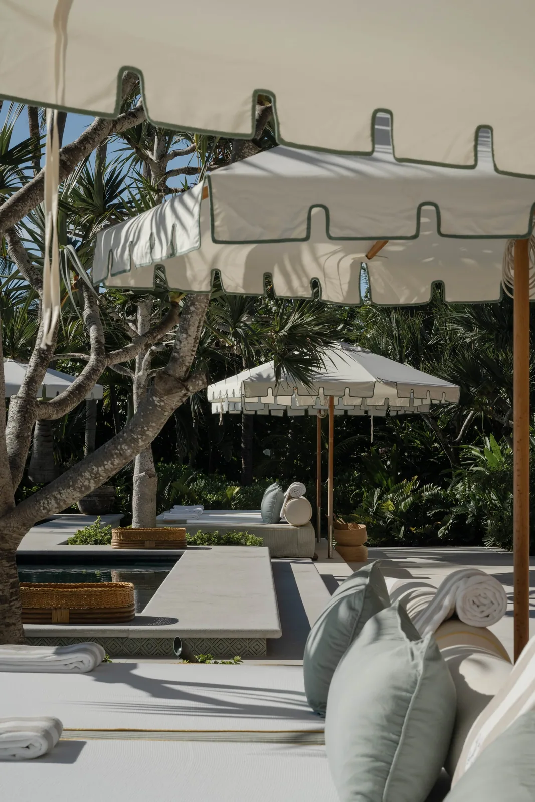 A white-canopied daybed set out on the sand at the beach club