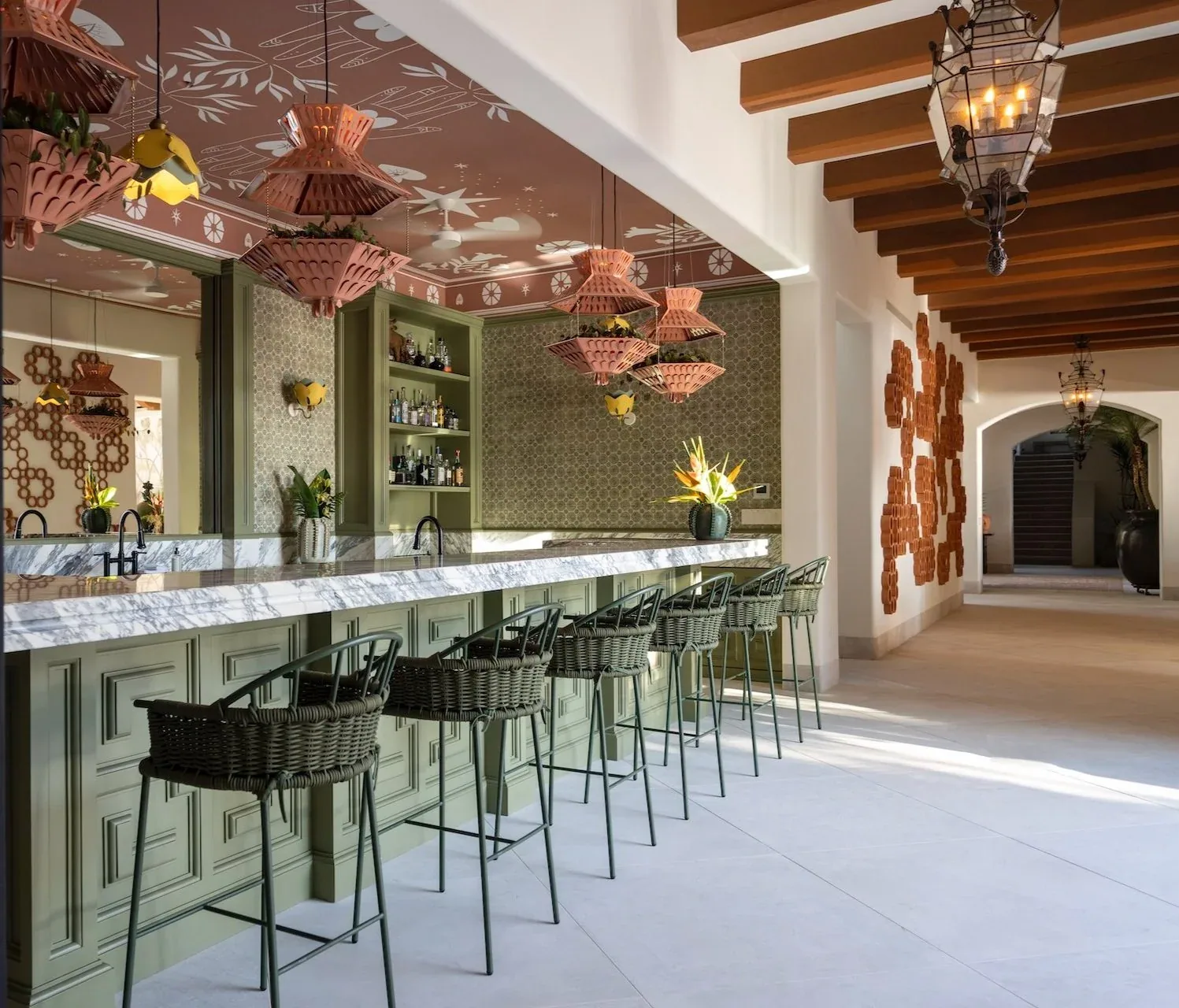 The estate&rsquo;s cocktail bar, its marble counter lined with stools under pink lanterns