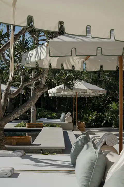 A white-canopied daybed set out on the sand at the beach club
