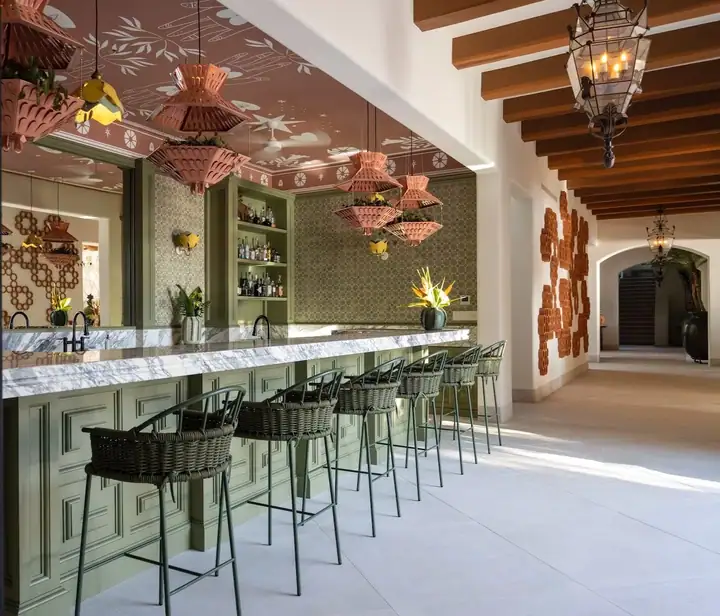 The estate&rsquo;s cocktail bar, its marble counter lined with stools under pink lanterns