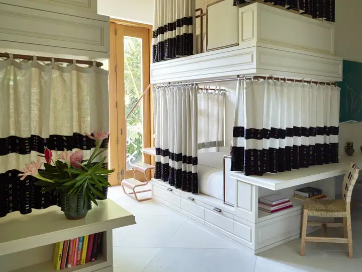 The four-twin bunk suite, each bunk curtained for privacy, with garden views