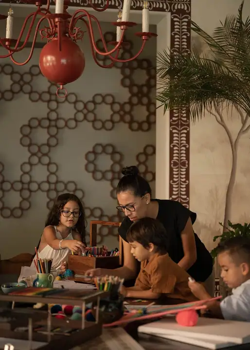 A kids&rsquo; club instructor working on a craft project with three children