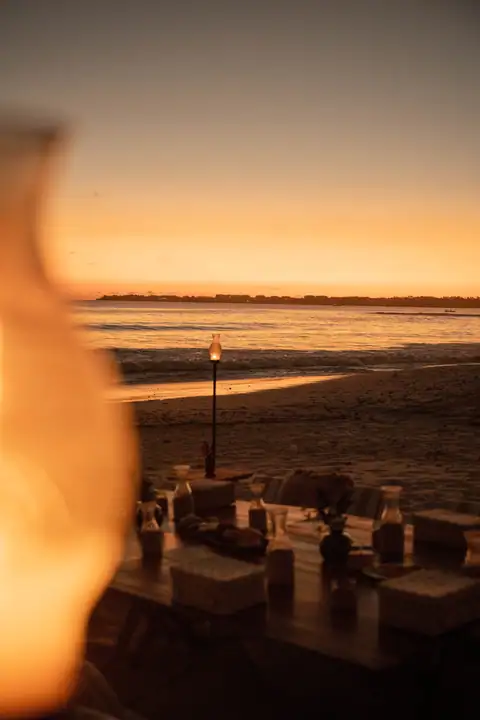 The oceanfront fire pit lit on the sand as the sun goes down
