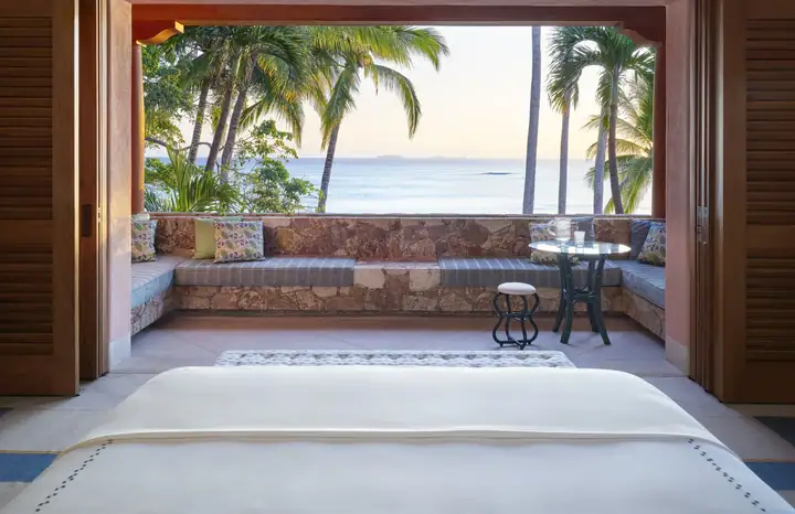 A terrace with folding doors thrown open to the palms and the ocean